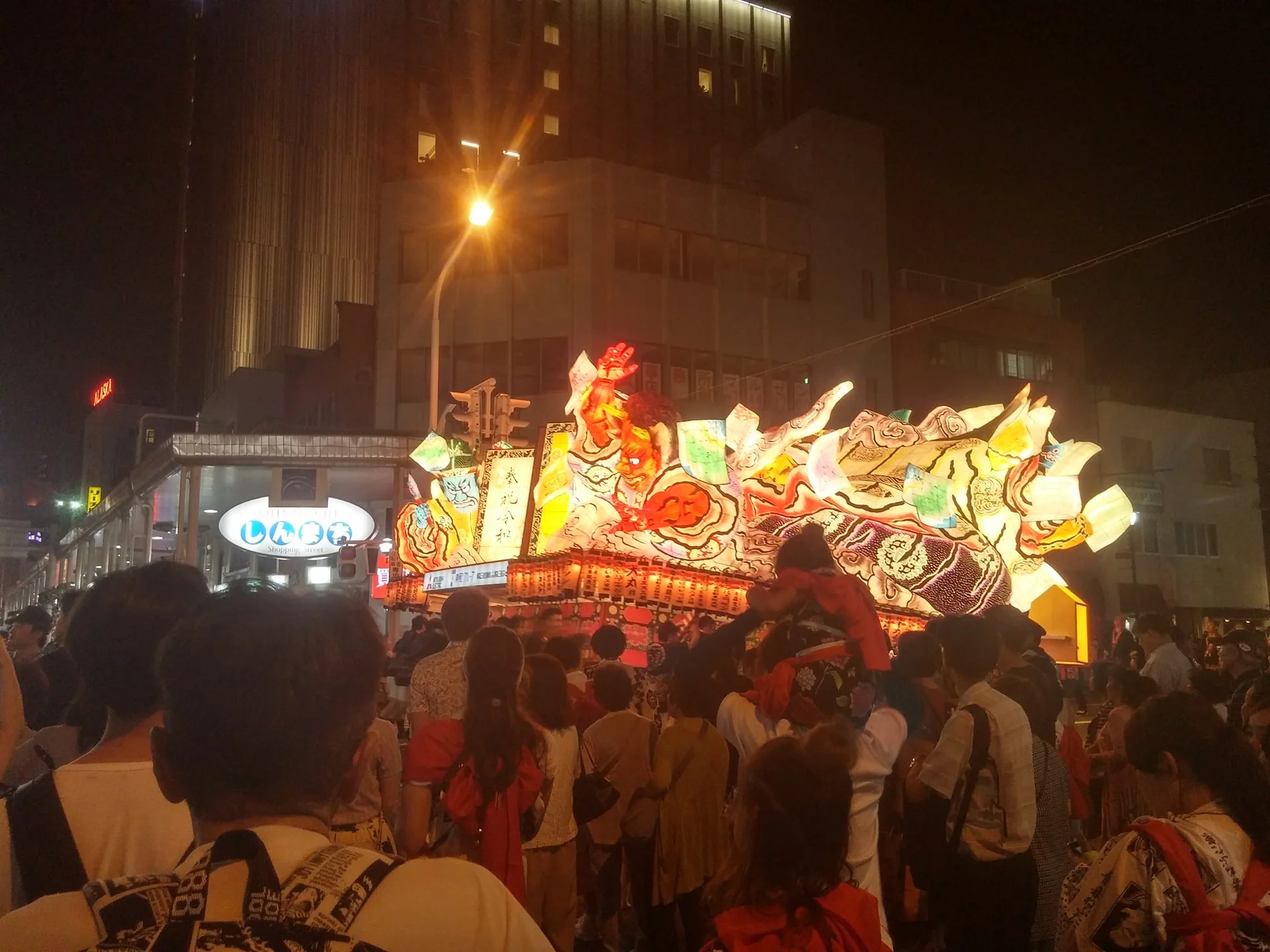 Illuminated Aomori Nebuta float moving along Shinmachi Street during the night parade
