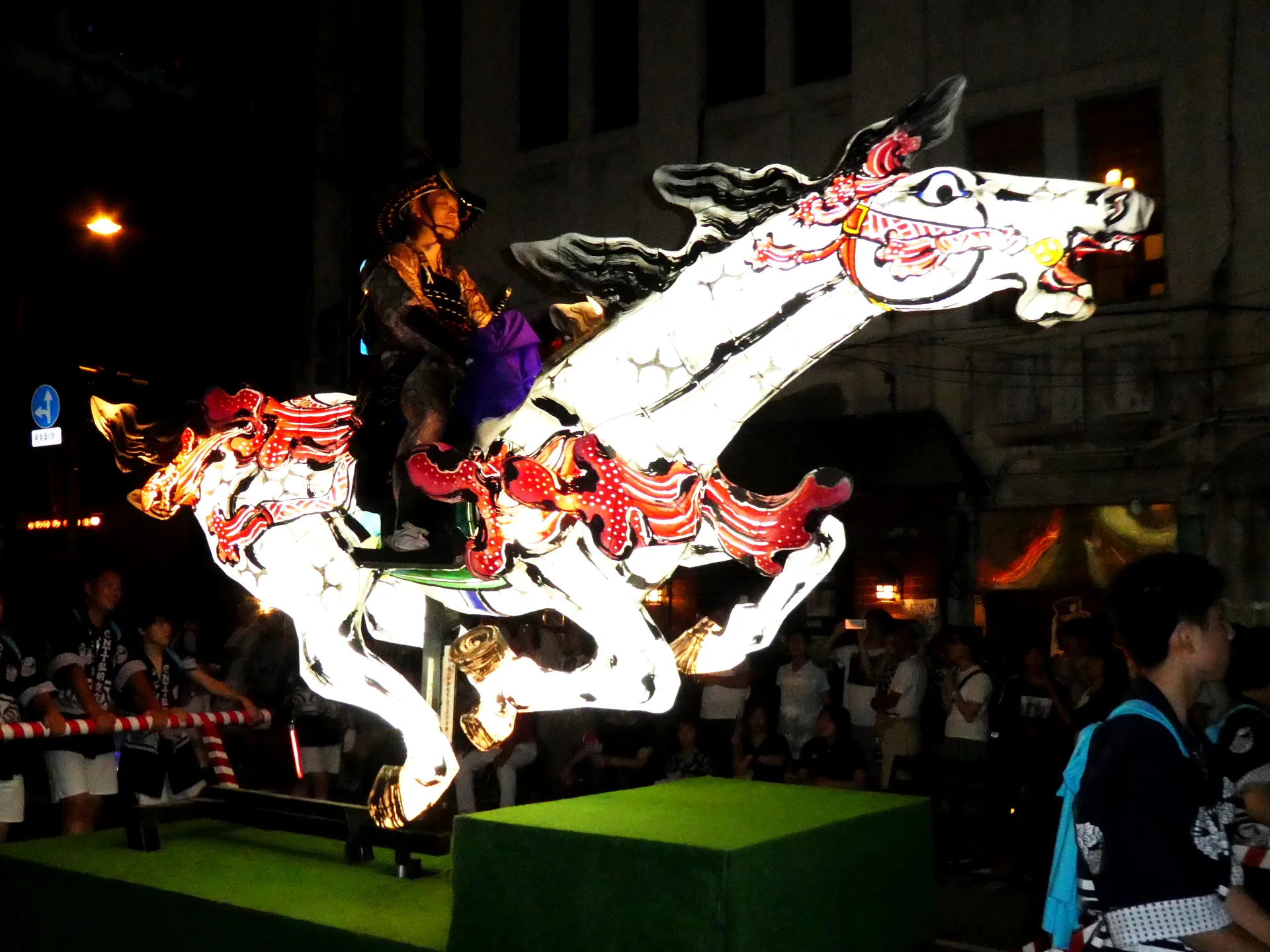 Large illuminated fan-shaped Hirosaki Neputa float moving through the city at night