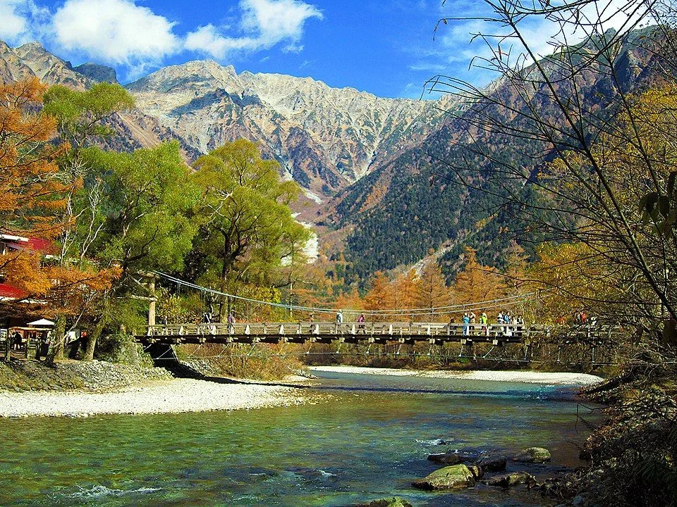 Kappa Bridge and the Hotaka Mountains in autumn, illustrating an October route dependent on mountain buses