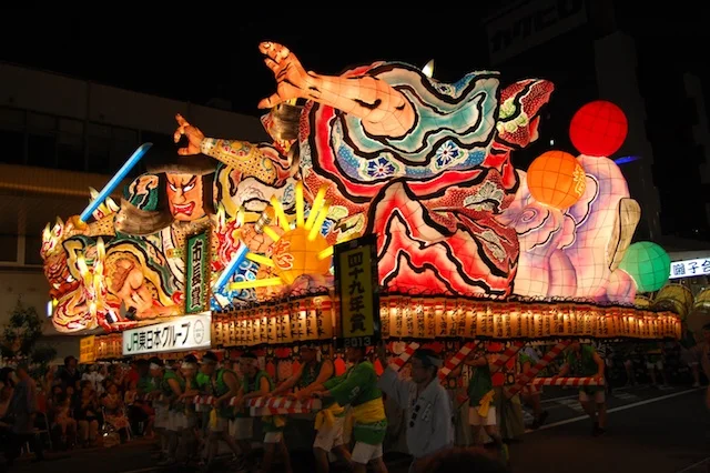 An illuminated Aomori Nebuta float at night, where families should choose their exit direction before the crowd moves