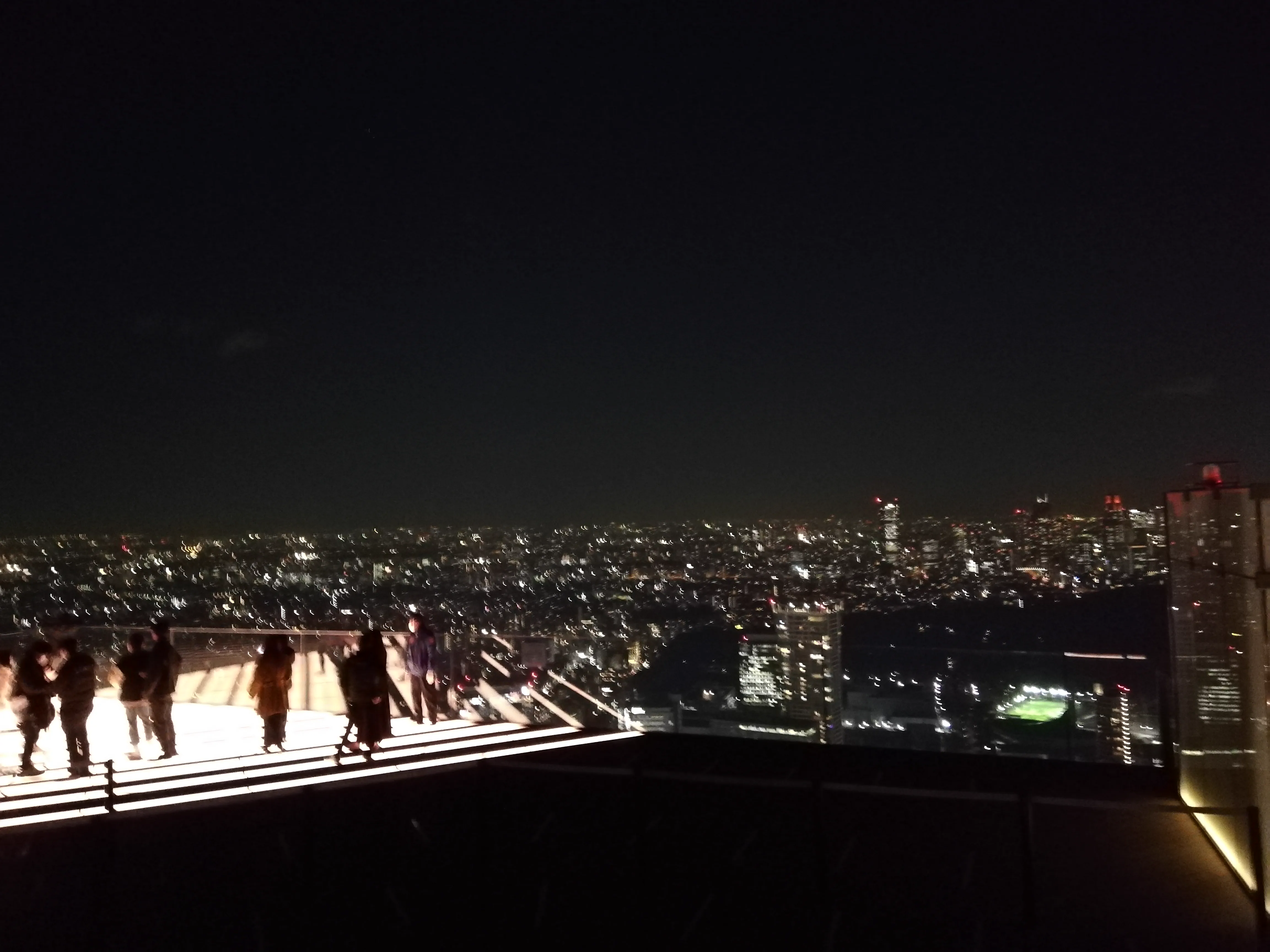 SHIBUYA SKY rooftop SKY STAGE at night; the open-air setting is the biggest difference versus other Tokyo observation decks