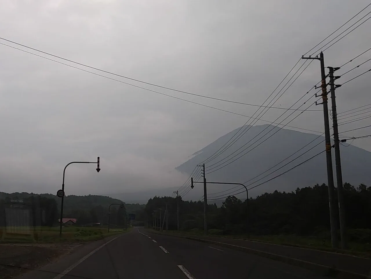 Road toward Niseko with Mount Yotei. Choose between a sightseeing charter and a one-way private transfer before paying for a full vehicle day.