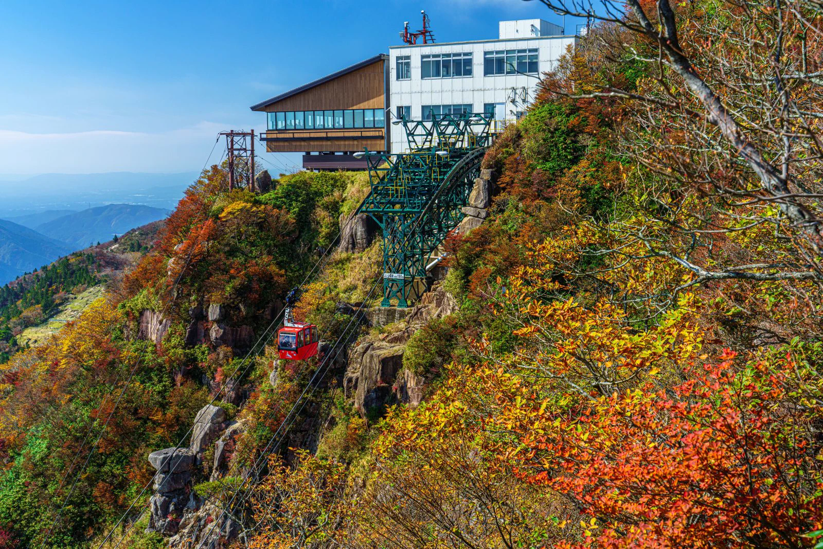 Gozaisho Ropeway passing through layered red, yellow and green autumn foliage on Mount Gozaisho